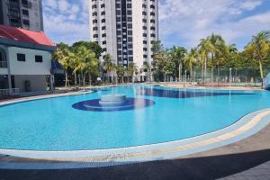 a large blue swimming pool with palm trees and a building at 3R3B Bukit Mewah Luxury Apartment. 24 hrs Security in Johor Bahru