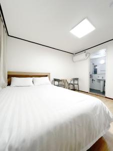 a bedroom with a large white bed and a bathroom at The Oakra Hotel in Jeju