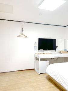 a bedroom with a bed and a desk with a television at The Oakra Hotel in Jeju