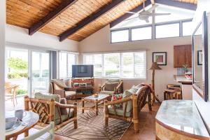 a living room with wooden ceilings and windows at OceanFront Kauai - Rhythm TVNC 4288 in Kapaa