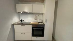 Il comprend une petite cuisine avec des placards blancs et une cuisinière. dans l'établissement APPARTAMENTI ALBANI, à Maglie