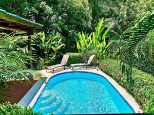 a swimming pool with two chairs and a table at Ocean Melody in Uvita