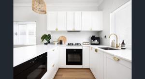 Biała kuchnia z białymi szafkami i czarną zmywarką do naczyń w obiekcie The South bay's home-Big RoomA w mieście Sydney