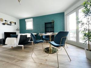 ein Wohnzimmer mit einem Tisch, Stühlen und einem Sofa in der Unterkunft Le Saphir in Rezé