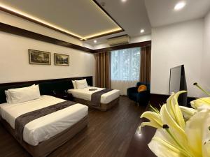 a hotel room with two beds and a tv at Mango Hotel - Ha Noi Railway station in Hanoi