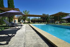 a swimming pool with two chairs and umbrellas at Le Mas Soli - Gîtes et Réception in Caderousse