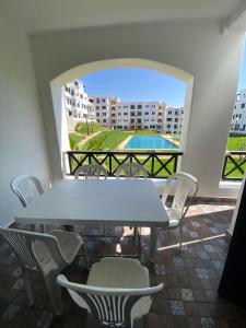 een tafel en stoelen op een balkon met een zwembad bij Lilac's Garden vue piscine in M'diq