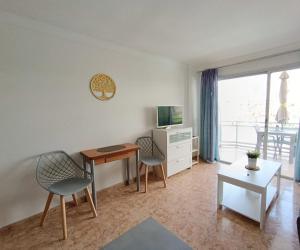 ein Wohnzimmer mit einem Schreibtisch, 2 Stühlen und einem TV in der Unterkunft in the heart of Playa del Inglés in San Bartolomé de Tirajana