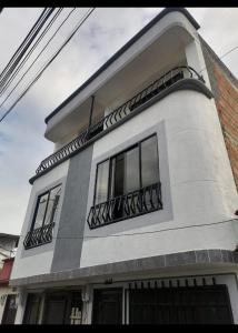 Edificio blanco con ventanas y balcón en Acogedor apartamento en la ciudad de las araucarias en Santa Rosa de Cabal