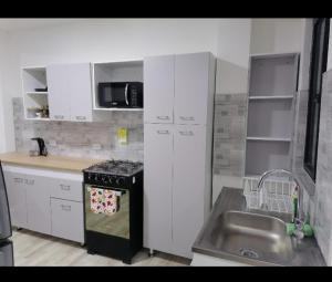 a kitchen with white cabinets and a sink and a stove at Acogedor apartamento en la ciudad de las araucarias in Santa Rosa de Cabal