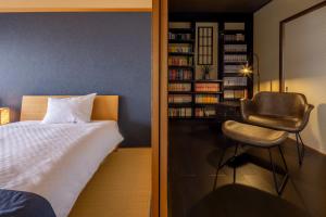 Machiya Oozora في كيوتو: غرفة نوم مع سرير وكرسي بجوار رف كتاب