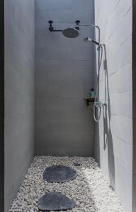a shower with a shower head and a stone floor at Canggu Hype in Canggu