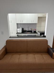 un sofá marrón en una cocina con armarios blancos en A dois passos do mar…, en Vila Velha