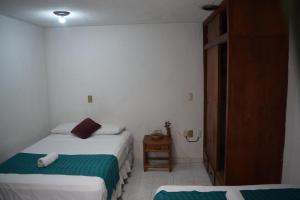 a small bedroom with two beds and a night stand at Casa Natura in San Cristóbal de Las Casas