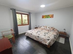 1 dormitorio con cama, escritorio y ventana en Casa con quincho y piscina privados, en Recinto