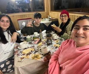 un grupo de personas sentadas en una mesa comiendo comida en Hostal Hunter en Puerto Montt