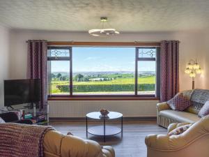 a living room with a couch and a large window at Lowesmuir Cottage in Cumnock