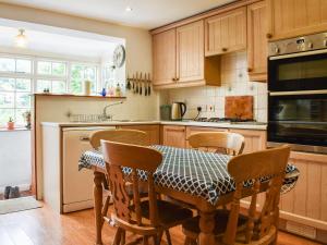 a kitchen with wooden cabinets and a table and chairs at The Cottage in Blakeney