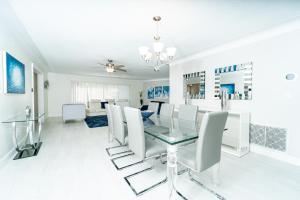 uma sala de jantar com uma mesa de vidro e cadeiras brancas em Waterfront Villa Heated Pool Spa Walk To Beach em Fort Lauderdale