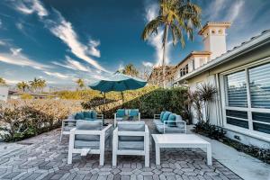un patio con mesa, sillas y sombrilla en Waterfront Villa Heated Pool Spa Walk To Beach, en Fort Lauderdale