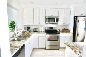 a kitchen with white cabinets and stainless steel appliances at Ocean Breeze Condo in Jensen Beach +26 photos