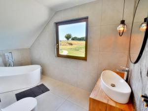 a bathroom with a tub and a toilet and a window at Comfortable holiday home, sauna hot tub included in Sulechowo +22 photos
