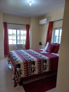 1 dormitorio con 1 cama grande y cortinas rojas en Sevelle Meadows 2 Extended Stay, en Spanish Town