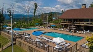 a hotel swimming pool with lounge chairs and umbrellas at Mins to Gburg Sleeps 8 Hot Tub Arcade Area Pool in Gatlinburg