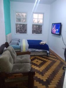 a bedroom with a bed and a couch and two windows at Sobrado Tranquilo Centro in Porto Alegre
