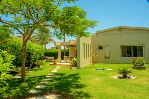 Villa 19, Amwaj Oyoun Resort - Beach- AquaPark Free Access في شرم الشيخ: منزل به ساحة بها عشب وأشجار