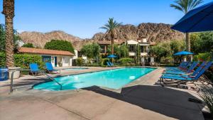 a swimming pool with chairs and umbrellas in a resort at LV009 Private Upstairs Studio w Mountain Views in La Quinta