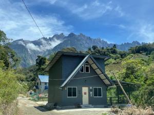 a small blue house with mountains in the background at The M Wanderlust Private Cabin in Ranau