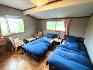 a bedroom with two beds and a table and chairs at Little Alaskan Guest House in Hakuba