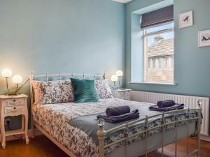 a bedroom with a bed with blue walls and a window at St, Georges Cottage in Holmfirth