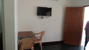 a room with a table and two chairs and a tv at Rainbow Guest House in Mahabalipuram