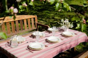 a table with plates and glasses on a striped table cloth at Karlamuiza Country Hotel in Kārļi