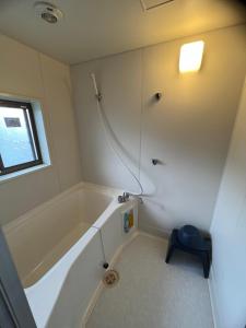a white bathroom with a tub and a window at Little Alaskan Guest House in Hakuba