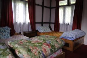 KalukにあるHitaishi Homestay - Bermiokのベッドルーム1室(ベッド2台、カーテン付きの窓付)