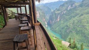 a wooden platform with a view of a river and mountains at Mã Pì Lèng EcoLodge in Mèo Vạc