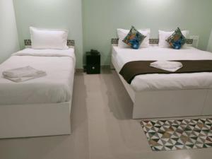 Habitación pequeña con 2 camas y paredes blancas. en Hotel BJ en Gangtok
