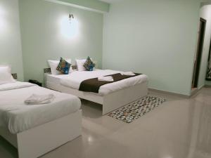 um quarto branco com 2 camas e um tapete em Hotel BJ em Gangtok