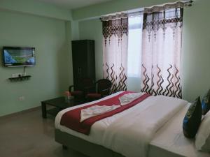 a bedroom with a bed and a window with curtains at Hotel BJ in Gangtok