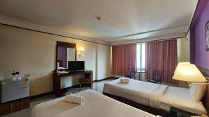 Habitación de hotel con 2 camas y escritorio en Songphanburi Hotel, en Suphanburi