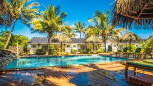 a swimming pool in front of a house with palm trees at Taha Tai in Hanga Roa