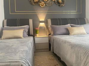 a bedroom with two beds and a table with a lamp at My Cozy 2-bedroom Apartment in Melaka