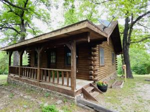 une cabane en rondins dans les bois avec une terrasse couverte dans l'établissement Cozy Cabin at Bear Mountain Log Cabins, à Eureka Springs