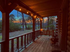 un porche de una cabaña con luces encendidas en Cozy Cabin at Bear Mountain Log Cabins, en Eureka Springs