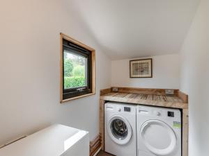 eine Waschküche mit einer Waschmaschine und einem Fenster in der Unterkunft Eeyores House - Uk43487 in Aldington