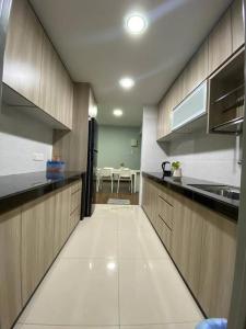 cocina grande con armarios de madera y fregadero en Family friendly multiple Parking 3bedroom apartment en Seri Kembangan