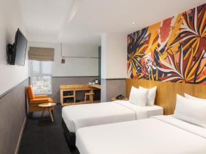 a hotel room with two beds and a desk at Swiss-Belinn Medan in Medan